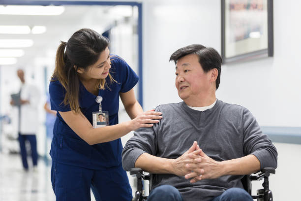 istock Nurse's aide stops to check on male patient in wheelchair 1206857204
