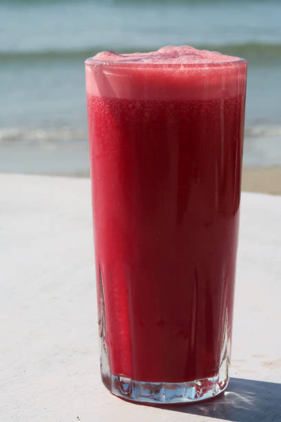 Stock photo showing al fresco dining at Palolem Beach, Goa, India. Fresh beetroot and carrot smoothie at breakfast table overlooking tropical beach paradise.