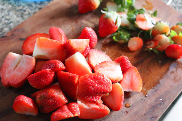 immagine di fragole appena sfiate e succose, frutta di fragole rosse biologica affettata su tagliere di legno - hulled foto e immagini stock