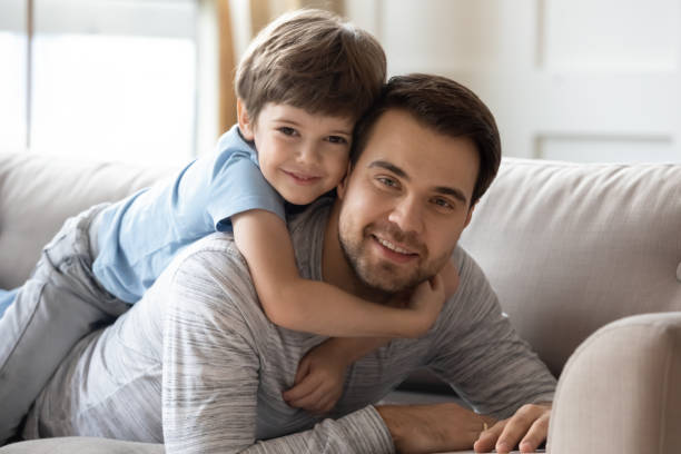 istock Carefree boy cuddling smiling dad, looking at camera. 1206859183