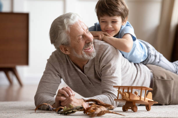 alegre familia de diferentes generaciones jugando juntos en casa. - grandchild grandparent child senior adult fotografías e imágenes de stock