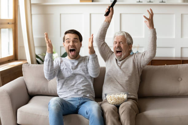 istock Overjoyed young man watching football match with middle aged father. 1206859209