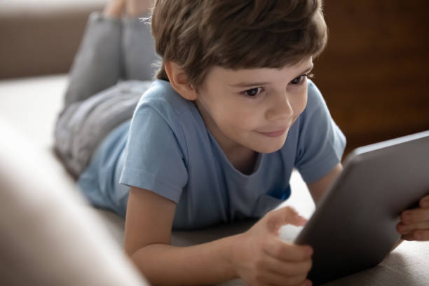 istock Smiling little school boy playing online game on computer tablet. 1206859720