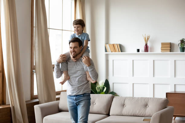 istock Happy young father holding on shoulders joyful son. 1206859737