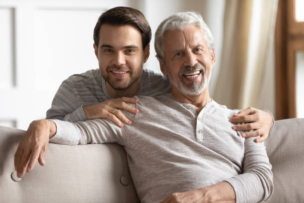 istock Head shot portrait young man embracing sitting on couch dad. 1206859746