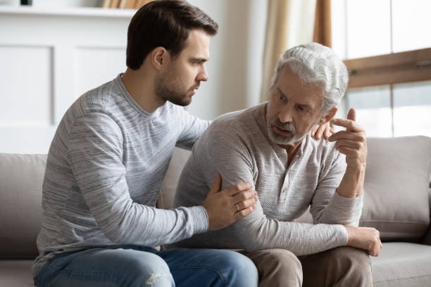 młody zestresowany człowiek pocieszający rozdrażnionego dojrzałego starego ojca. - old senior adult one person rudeness zdjęcia i obrazy z banku zdjęć