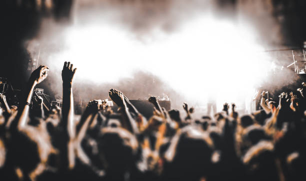 los jóvenes felices se divierten y bailan en un club nocturno durante un concierto - se centran en las manos con dj en el fondo - filtro de naranja negro - músico de rock fotografías e imágenes de stock