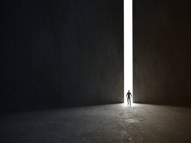istock Abstract man in dark concrete interior with glowing doorway and light rays coming in. 3d rendering 1206861626