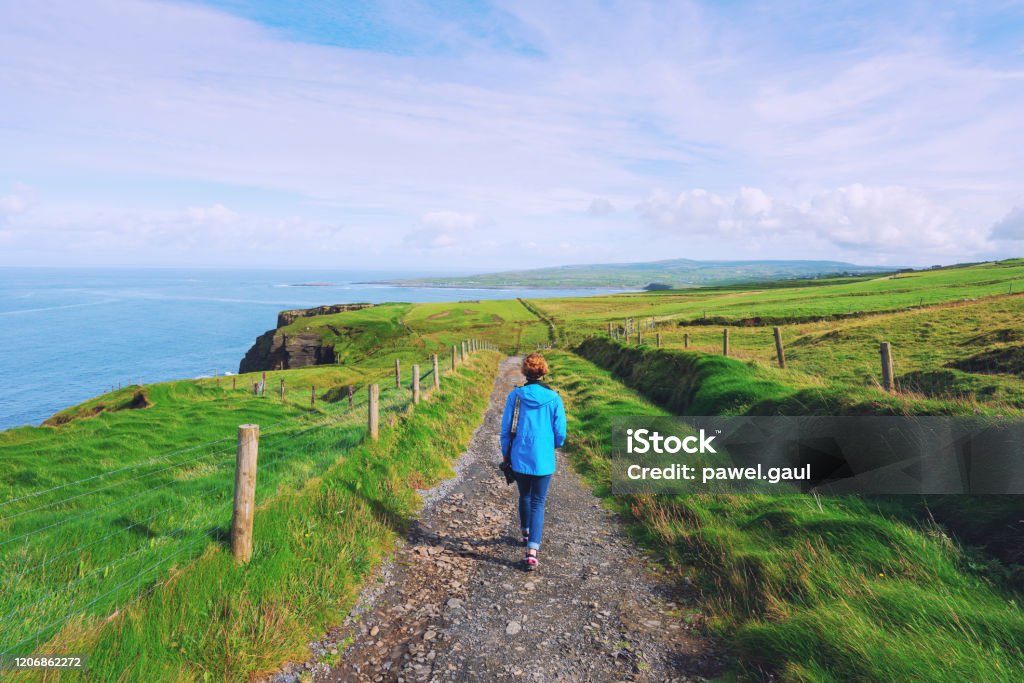Woman trekking on Cliffs of Moher walking trail in Ireland Ireland Stock Photo