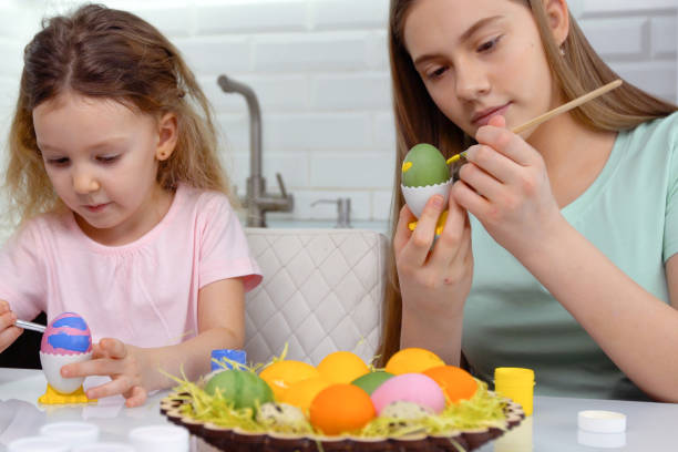 istock Happy easter. Two sisters painting Easter eggs. Happy family children preparing for Easter. Cute little child girl wearing bunny ears on Easter day 1206864966