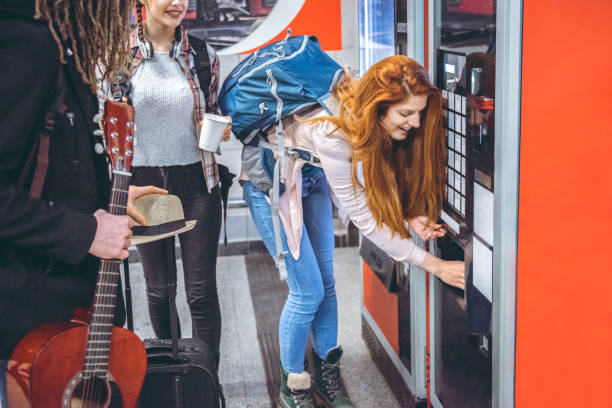 los viajeros jóvenes compran café en una máquina expendedora - vending machine fotos fotografías e imágenes de stock