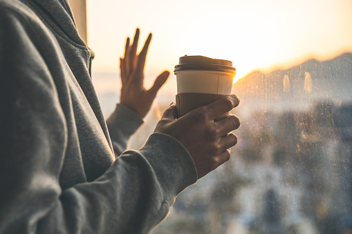 Hand holding coffee cup by window