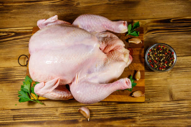 istock Raw whole chicken with spices on a wooden table. Top view 1206869988