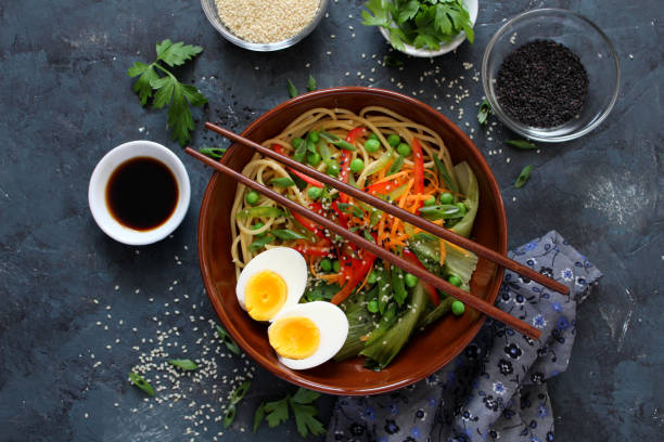 istock Noodles with vegetables and eggs in bowl on dark background. 1206871945