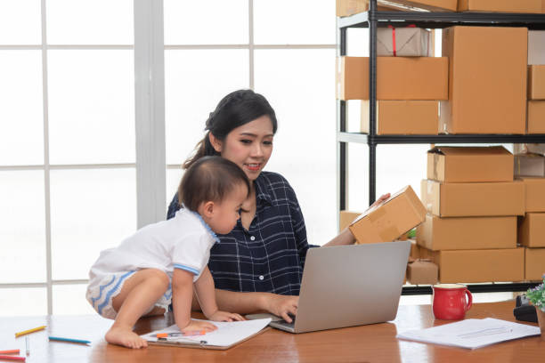 istock Pretty young single mom working at home on a laptop computer, and baby daughter need her attention. Mother play on laptop with daughter. 1206872130