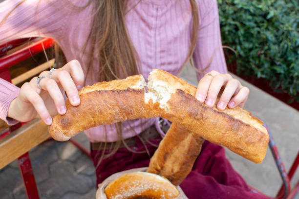 istock fresh broken baguette in female hands 1206872563