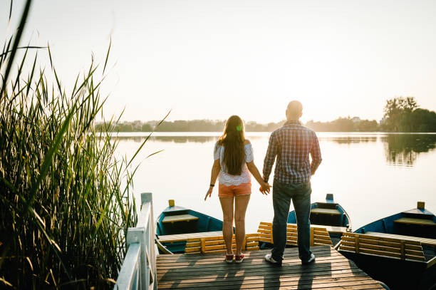 istock Couple holding hands looking in the sunset on pier. Back view. 1206874904