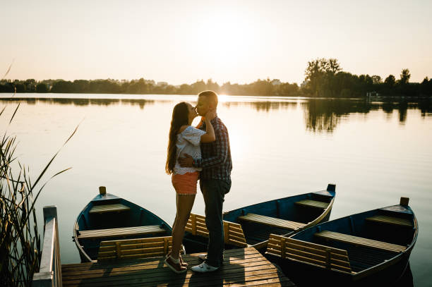 istock Couple hugging and kissing at sunset on pier. Side view. 1206874907
