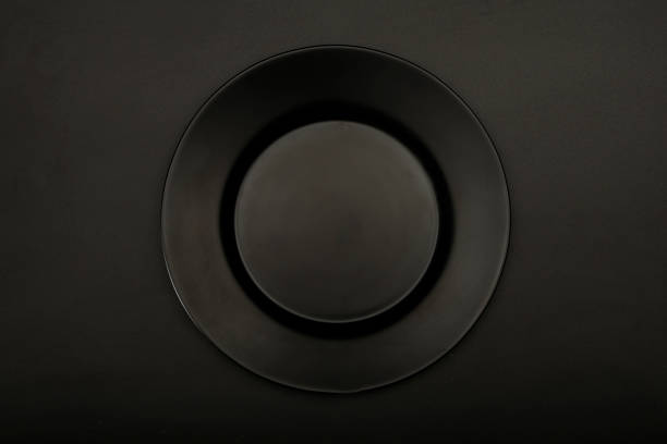 istock Black ceramic plate mock up for design isolated on black background, close-up top view. Copy space. 1206876016