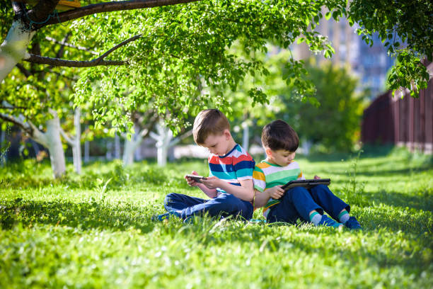 istock Two brother kid is lying on the grass with tablet. 1206877869