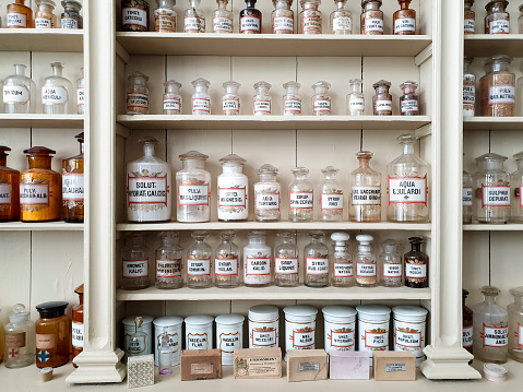 Chemicals for making medicine in historic pharmacy, glass bottles standing on shelves, labeled in Latin script