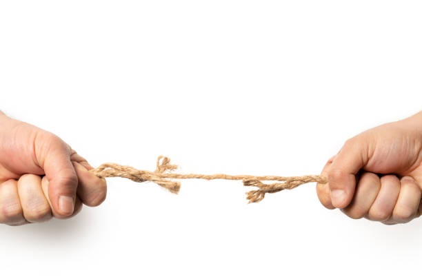 istock Two man are pulling old frayed rope in opposite direction with strength. Isolated on white. Compotetion in business concept. 1206885021
