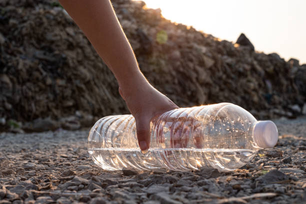 istock Close up Hand picking up  clear plastic bottle drop on the ground at mountain large garbage background, These waste come from urban and industrial areas can not get rid of 1206887517