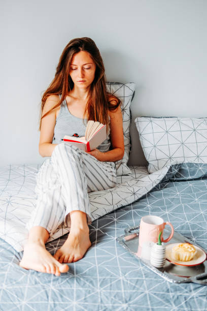 istock Young redhead woman reading in bed. Lazy moring routine. 1206889319
