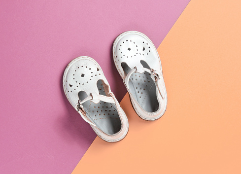 White leather children's sandals on colored pastel background. Top view