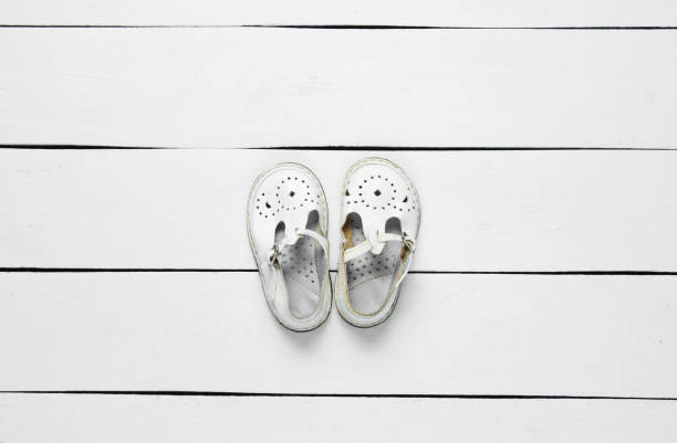 istock White leather children's sandals on white wooden background. Top view 1206889604