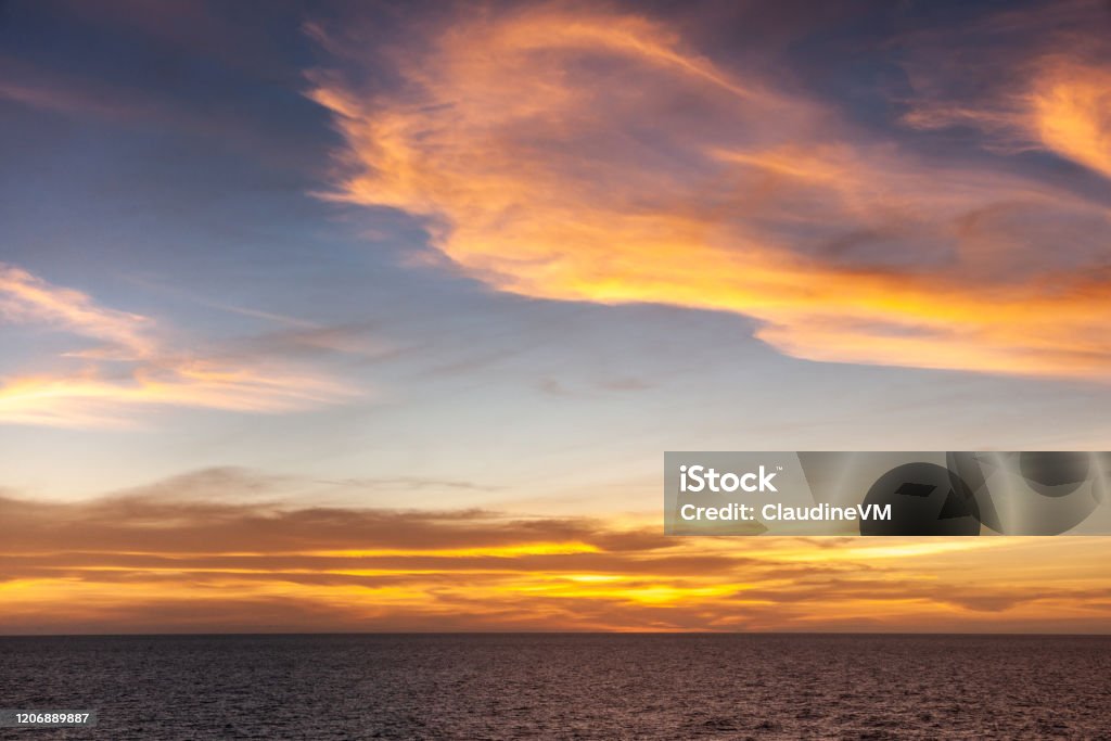 Red sunset over Arafura Sea, Australia. Arafura Sea, Australai - December 2, 2009: Red sunset with brown to orange and yellow clouds in light to dark blue sky over dark blue sea. Australia Stock Photo