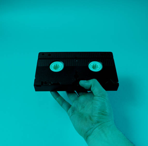 istock Male hand holds retro video cassette. Blue neon light 1206891096