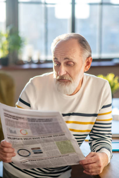istock Grey-haired bearded man in striped sweater looking doubtful 1206891374