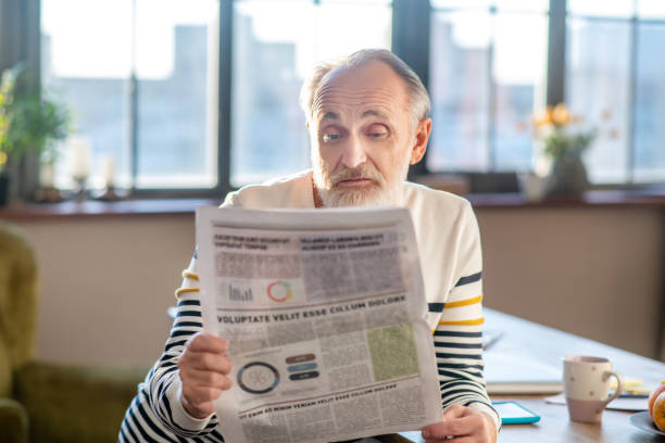 istock Grey-haired bearded man in striped sweater looking surprised 1206891405