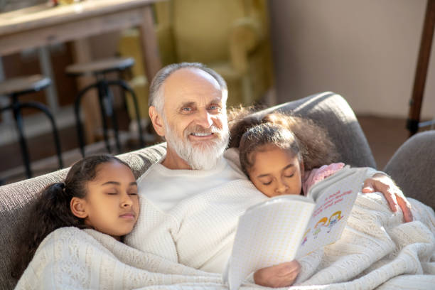 istock Two girls sleeping on the sofa hugging their granddad. 1206891552