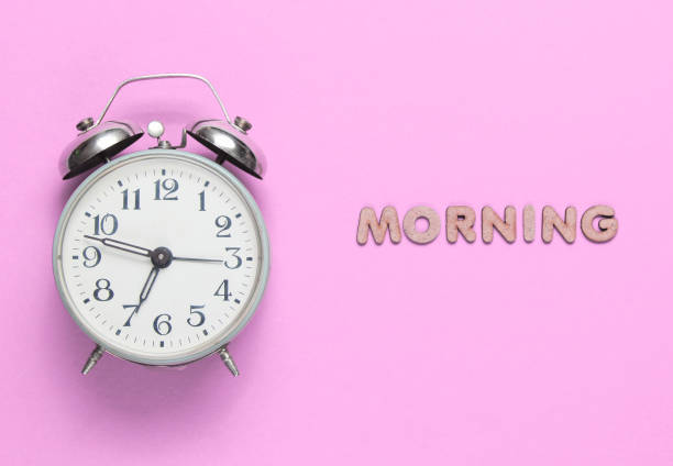 istock Retro alarm clock on pink background with text morning with letters. 1206891839