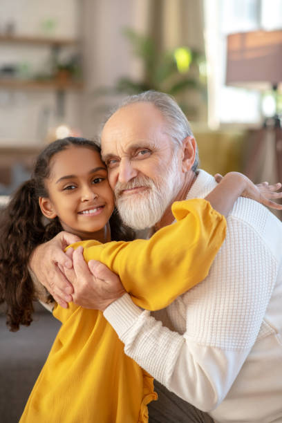 istock Grey-haired man and a dark-skinned girl looking joyful 1206892015