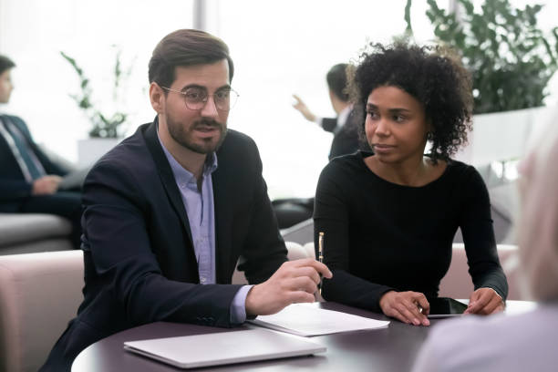 istock Assistant watching young confident businessman discussing contract terms with clients. 1206893428