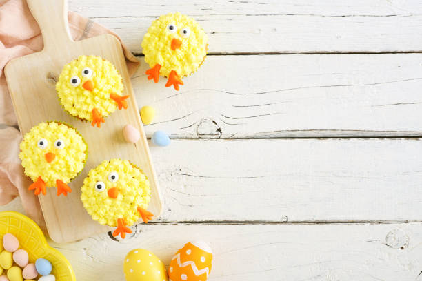 istock Spring chick cupcakes, top view side border with copy space against a white wood background 1206893734