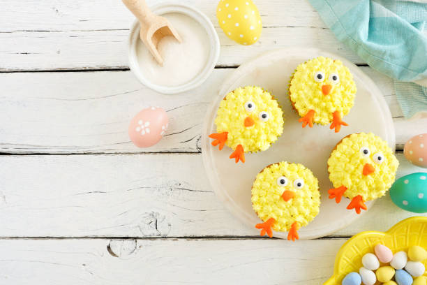 istock Spring chick cupcakes, top view corner border with copy space over a white wood background 1206893738