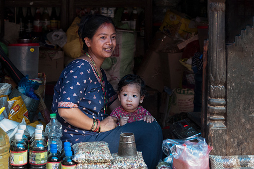 Unidentified Nepalese Newari woman with her child in a haberdashery in Bhaktapur, listed as a World Heritage by UNESCO for its rich culture, temples, wood artwork - Nepal
