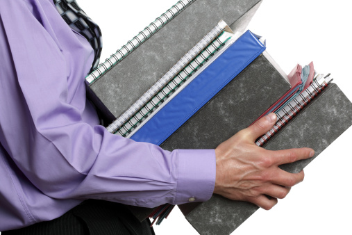Businessman carrying a stack of files, concept for overwork, busy or multi-tasking