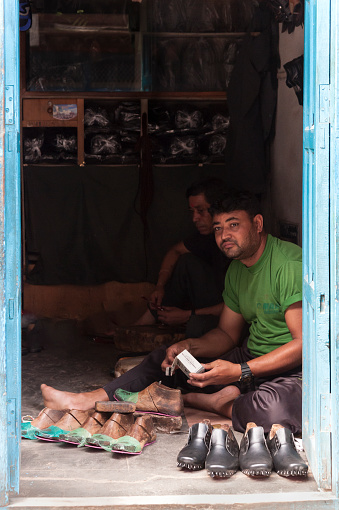 Unidentified Nepalese Newari shoemakers in their shop in  Bhaktapur, listed as a World Heritage by UNESCO for its rich culture, temples, wood artwork - Nepal