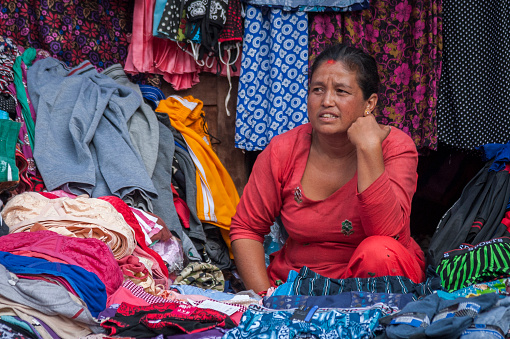 Unidentified Nepalese woman selling clothes in Bhaktapur, Nepal, listed as a World Heritage by UNESCO for its rich culture, temples, and wood artwork