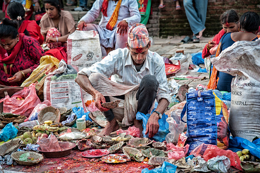 Unidentified Nepalese Newari man selling vegetables and flowers in  Bhaktapur, listed as a World Heritage by UNESCO for its rich culture, temples, wood artwork - Nepal