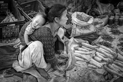 Unidentified Nepalese woman with a little child selling vegetables in Bhaktapur, listed as a World Heritage by UNESCO for its rich culture, temples, wood artwork - Nepal