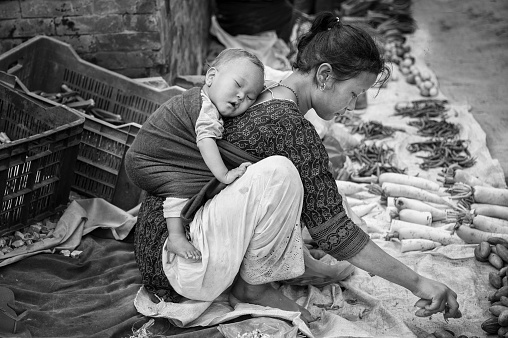 Unidentified Nepalese woman with a little child selling vegetables in Bhaktapur, listed as a World Heritage by UNESCO for its rich culture, temples, wood artwork - Nepal