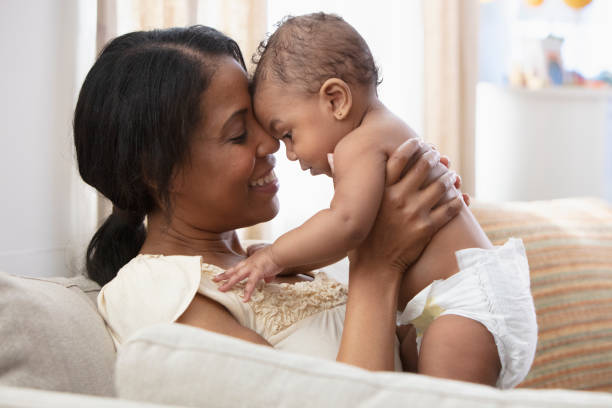 istock Black woman playing with baby daughter on sofa 1206896893