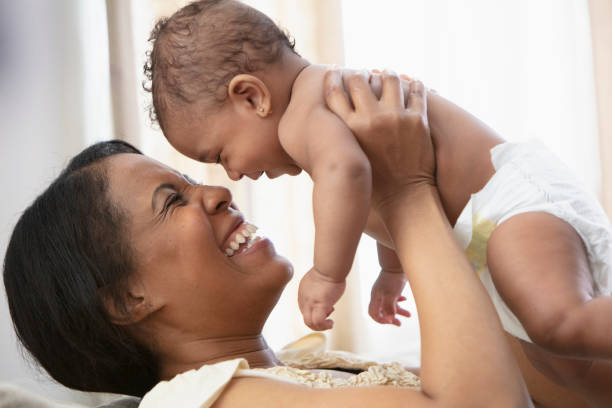 istock Black woman playing with baby daughter on sofa 1206896986