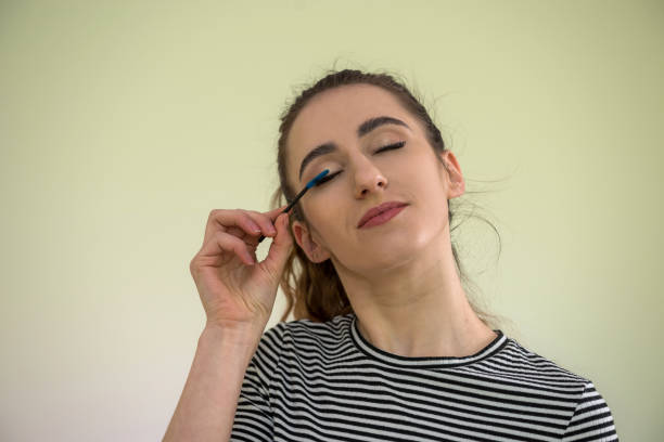 istock Beautiful girl paints eyelashes morning before work isolated on green 1206898215